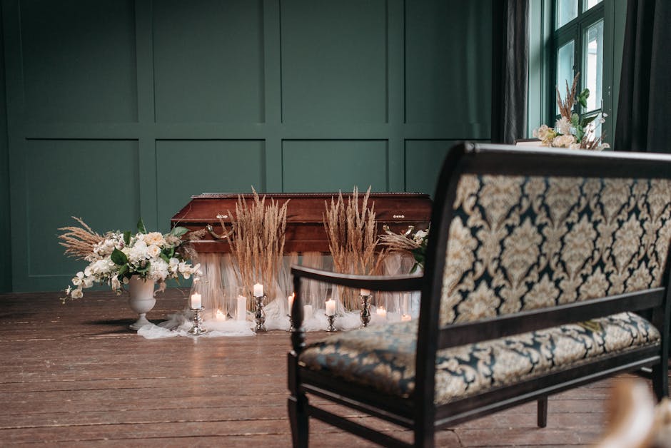 An indoor floral arrangement setup featuring a large, elegant bouquet of white roses, lilies, and greenery in a white ceramic vase on the left side, complemented by dried pampas grass stalks in the ce