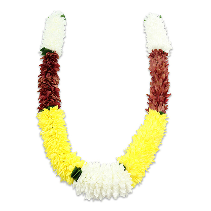 A vibrant, U-shaped mala is photographed against a pristine white backdrop, the lighting arranged to reveal the rich interplay of colour and texture while a faint shadow gives the piece dimensionality. Starting at the top of each arm a substantial section of compact, creamy white blooms-resembling tiny chrysanthemums or clustered jasmine-creates a serene, fluffy collar that frames the garland. Directly beneath, a concentrated band of maroon or deep reddish-brown fabric flowers introduces a darker, grounding tone, its tightly packed petals lending a velvet-like depth to the upper arcs. The longest and most prominent section is a cascade of bright yellow blossoms; each yellow flower is layered and plush, contributing to a generous, rolling volume along the lower U that feels celebratory and warm. Where the two yellow stretches meet at the bottom, a broad, lush cluster of pure white chrysanthemum-like blooms forms the central focal point, accented at intervals by small dark green leaves which act as subtle separators between colour blocks. The synthetic nature of the materials is evident in the uniformity and resilience of the petals, yet the arrangement preserves the traditional symbolism-white for purity, maroon for devotion, yellow for prosperity-and the craftsmanship is meticulous, with thousands of individual fabric petals composed to mimic natural bloom density. In Epping, such garlands are often seen during communal pujas, temple ceremonies near the high street, wedding entrances, or festival altars; the design conveys reverence, welcome, and a continuity of cultural tradition crafted with care.