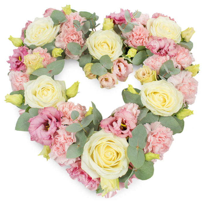 A generous heart-shaped tribute dominates the image, lush and full, set against a clean white background that makes every pastel petal appear luminous. The heart is carefully constructed, its outline perfectly smooth, as though traced by a steady, caring hand. Creamy ivory and soft lemon-yellow roses are positioned at key points around the shape, their tightly layered petals opening into full, cup-like blooms that radiate a sense of purity, devotion, and steady affection. Clustered in between these larger roses are many light pink carnations, their frilled, textured petals forming cushions of softness that fill the heart with volume and warmth. Richer tones come from deeper pink and mauve lisianthus flowers, which open more loosely and reveal subtle darker centres, adding depth and a graceful, almost wistful elegance. Tiny yellow-green buds appear at intervals, suggesting fresh blossoms just about to open, a quiet reminder of continuity and hope. Weaving through all of this are strands of silvery-green eucalyptus, the round, matte leaves creating cool highlights that balance the romantic pastels. The foliage curves gently along the inner and outer edges of the heart, helping define its shape while evoking the tranquil greenery of Epping's nearby forest and parkland. The arrangement feels like a tender embrace, a floral symbol a family in Epping might place beside a loved one's coffin or at a memorial service. It speaks without words of love, sympathy, and cherished memories, carrying the calm reassurance and craftsmanship you would expect from an experienced local florist who understands how flowers can honour a life with quiet beauty.