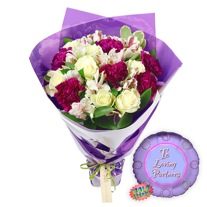 The image shows a beautifully styled romantic bouquet with a coordinating balloon, photographed against a bright white background that highlights every colour and texture. At the centre is a full, hand-tied arrangement that could easily have been created by an expert florist in Epping, moments before same-day delivery across the town. Creamy white roses, with their petals still closely wound, take the lead. Their smooth, spiralling forms bring a sense of calm purity and classic romance. Around and between them sit deep magenta and burgundy carnations, their many ruffled petals forming lush clusters that add depth, richness, and a slightly vintage feel. Interlaced among these are white alstroemeria, or Peruvian lilies, each floret bearing fine reddish-brown speckles and stripes inside the throat, like delicate brushstrokes. The flowers are framed by assorted greenery, including glossy leaves and variegated foliage with pale edges, providing a fresh, leafy backdrop and gentle contrast to the bold blooms. The bouquet is wrapped in two layers that work together to create a contemporary, polished look. Closest to the stems is a crisp white paper wrap, visible as a clear diagonal band that anchors the design. Over this sits a layer of translucent purple cellophane, softly crinkled and rising above the flowers in fluttering points, giving a luminous, almost ethereal glow around the arrangement. The stems are gathered tightly at the base and tied with a slender band of bright green satin ribbon, which is finished in a neat, understated bow. A small light brown rectangular gift tag hangs beneath, ready for a heartfelt message. To the right side of the bouquet lies a round metallic purple foil balloon with a scalloped, rosette-like edge. In the centre, a lighter lavender circle carries the inscription To Loving Partners in flowing pink script, and a jagged rainbow holographic sticker clings just below, hinting at a special reflective finish. The overall mood is joyful yet intimate-a perfect ensemble for anniversaries, date nights at home in Epping, or quiet celebrations of long-standing love.