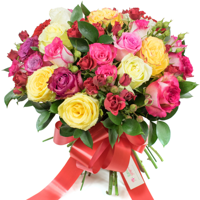 A full, rounded bouquet of premium roses sits elegantly against a clean white background, a study in colour, texture and seasonal cheer. The arrangement pairs large open hybrid tea roses-plump and layered-with clusters of smaller spray roses and numerous tight buds to create a lush, domed silhouette. The palette is deliberately joyful: brilliant yellow roses warm the centre, creamy ivory blooms soften the composition, and a sweep of pinks from soft blush to vibrant fuchsia meets deep burgundy and classic crimson for dramatic contrast. Glossy dark green foliage, likely ruscus or salal, is skilfully placed between clusters to provide depth and a polished verdant frame that emphasizes each petal's tone. The gathered stems are bound with a wide bright red satin ribbon tied into a prominent bow; the ribbon's sheen and long tails add a festive flourish that catches light along its folds. Tucked into the ribbon is a small white tag stamped with a colourful logo and the greeting Happy Holidays, offering a seasonal sentiment that feels personal and considered. Texturally the bouquet invites touch in description: the velvet softness of rose petals, the crisp surface of new leaves, the firm little beads of unopened buds. A clean, slightly citrus-tinged rose fragrance seems to lift from the composition, conjuring a brisk walk through local green spaces like Epping Forest or a cosy moment beside a café on Epping High Street. Perfect for birthdays, anniversaries, Valentine's or seasonal greetings, this bouquet delivers colour, craft and heartfelt intent to recipients across the Epping area.
