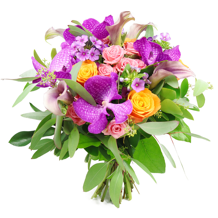 Captured against a bright, uncluttered white background, this opulent bouquet glows with a sophisticated palette of purples, oranges, pinks, and layered greens. At its centre, large Vanda orchids unfurl in saturated purple and fuchsia, their petals finely netted with paler speckles that hint at tropical origins and draw the eye into their intricate patterns. Threaded through this drama are vibrant orange roses in various stages of opening: some are tight, rounded buds, while others have begun to reveal their spiralling hearts, their warm tangerine tones suggesting sunsets over the edges of Epping Forest. Soft blush and pastel pink roses bring a gentler mood, their petal edges slightly ruffled, adding a romantic, almost vintage softness amid the bolder shades. Rising elegantly above the rounded dome of the bouquet, graceful calla lilies in dusky mauve and plum curve like small sculpted trumpets, their smooth surfaces catching the light and giving the arrangement a refined, contemporary line. Surrounding all of this, a generous collar of foliage provides structure and natural movement: fine, silvery eucalyptus stems arc outward with a slightly matte sheen, while darker, glossy leaves add solidity and depth. Scattered between the focal flowers, clusters of tiny lavender or lilac filler blooms lend a starry, textural detail, softening the transitions between colours. The flower stems are clearly visible at the base, neatly gathered to show a true hand-tied finish, as a local florist in Epping might prepare for a same-day delivery. The overall feeling is celebratory yet polished, ideal for an anniversary dinner on Epping High Street, a special birthday in Theydon Bois, or as a luxurious centrepiece bringing the spirit of a well-tended garden indoors.