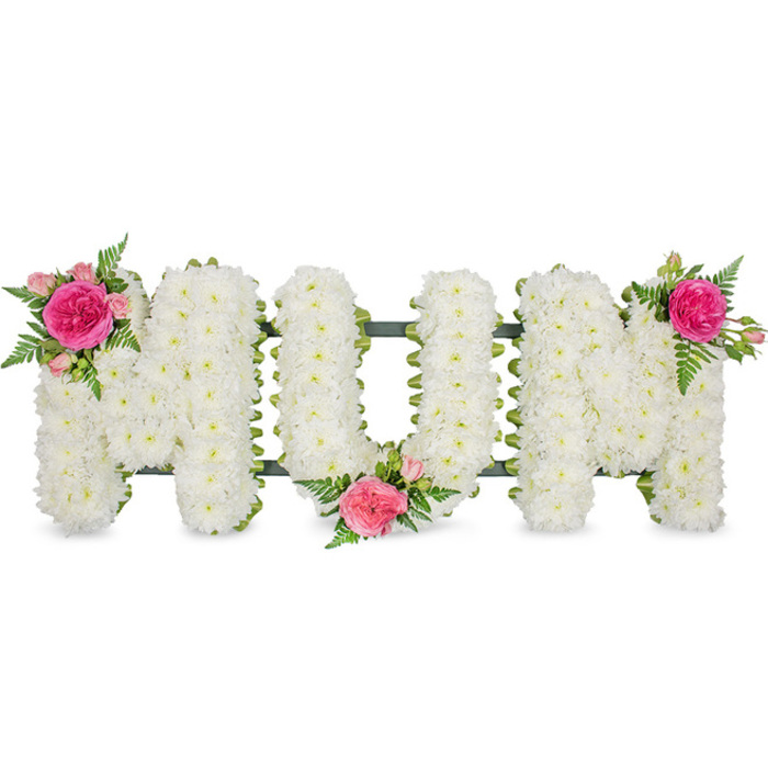 A beautifully composed sympathy tribute spells out MUM in large, confident block letters, carefully arranged so the word sits clearly centred against a plain white background. Each letter is meticulously covered with small white spray chrysanthemums, their compact petals layered one over another until no gaps remain, giving the arrangement a soft cushion effect reminiscent of freshly fallen snow. The brightness of the white blooms speaks of purity and remembrance, while their uniform texture provides a calm, steady rhythm to the design. Along the base, a slim band of deep green ribbon and the underlying frame add definition and hold the piece securely, hinting at the skilled craftsmanship behind such floral lettering. Three elegant accent arrangements bring colour and emotion. On the top left of the first M, a fuchsia garden rose opens luxuriously beside paler pink spray roses and buds, all cradled by airy sprays of green fern. In the gentle dip at the bottom of the U, another cluster is tucked in, nestling into the white flowers like a cherished memory at the heart of the piece. The final cluster on the upper right of the second M completes the visual journey, echoing the first and giving balance and flow. The contrast of luminous white, vibrant pink, and fresh green feels both uplifting and serene, like a quiet corner of a garden in Epping on a mild afternoon. Created with the same care a family would feel, this MUM tribute seems ready to rest beside a coffin, on a hearse, or at a graveside, carrying a simple, heartfelt message of gratitude, love, and farewell. Its presence suggests gentle fragrance-soft chrysanthemum notes and sweet rose perfume-offering a moment of solace to those gathered to say goodbye.