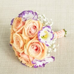 In this radiant bouquet, the artistry and soul of Epping's finest florists converge, celebrating romance and community in every gentle curve. Lush peach and apricot roses blossom at the heart, their soft, sun-warmed petals inviting the sense of touch and scent, recalling the tranquil gardens that border Bell Common and the town's heritage churches. White lisianthus flowers peek through, their unique ruffled petals dusted with lively shades of purple, each bloom capturing the playful spirit of local summer fêtes. Flurries of tiny white gypsophila, light as clouds over Homefield Close, dance between the larger blooms, bringing softness and air, balancing the warmth with tradition. Each stem is gathered by hand, wrapped in a smooth, peach-toned satin ribbon, and finished with dainty pearls, as if echoing the elegance of a timeless wedding on the Green. This bouquet seems designed not just for a celebration, but as an heirloom of memory-fit to be carried through a historic church ceremony, placed with pride as a centrepiece in a local home, or simply cherished for its craftsmanship and gentle, refined palette. Portrait lighting, filtered like morning sunshine through a forest clearing, highlights each petal's glow, making this arrangement a poetic and sophisticated floral choice for Epping's most cherished occasions.