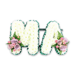 Set against a clean white backdrop, this funeral flower arrangement spells out the letters MA in bold, comforting forms, echoing the kind of personal tributes often created for families in Epping and the neighbouring villages. Both the M and the A are completely filled with immaculate white chrysanthemums, their small, rounded heads pressed closely together so that no gaps show through. The blooms form a soft, quilted texture that looks almost like freshly fallen snow, yet each petal remains clearly defined. Around the very edges of the letters runs a rich, dark green satin ribbon, gently frilled and folded to create a delicate border. This ribbon outlines every angle and point, giving the tribute a crisp, finished silhouette. At the base of the left leg of the M and the base of the right leg of the A, matching flower sprays introduce gentle colour. Here, pale pink roses and muted lilac roses open in layered swirls, mingling with smaller pink spray roses and subtle buds. Wisps of fern and fresh green foliage thread through the roses, bringing a hint of garden softness and movement. The tribute feels both structured and tender, suggesting a message of love and respect for a mother, Ma, or someone remembered by the initials M.A. Although the photograph is simple and uncluttered, the craftsmanship is evident in the precise spacing, the symmetry of the side clusters, and the harmony of white, pink, and purple tones. It is the kind of custom letter tribute a local Epping florist might prepare for a church service, crematorium farewell, or graveside gathering, offering a quiet symbol of connection, memory, and affection.