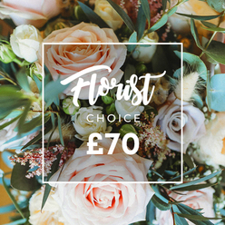 An intimate, artfully lit overhead photograph of a premium 'Florist Choice' bouquet, where pastel romance meets natural texture. The composition is filled with large, open roses in gentle blush pink and warm peach, their velvety petals spiralling outward; creamy white spray roses and pale lilac roses sit like quiet punctuation among them. Small pink florets and airy filler flowers create a misty, delicate veil that threads through the arrangement, while clusters of tiny pink berries or waxflower add pinpoint interest. Dried, cream-toned grasses and seed pods provide a subtle, rustic counterpoint, lifting the bouquet with soft, tactile volume and a muted, papery texture. Eucalyptus leaves - round, dusty blue-green - trail through the flowers, offering cool tones and a hint of invigorating scent that calls to spring gardens. A clean white rectangular frame overlays the image, anchoring the eye to an elegant script that reads "Florist Choice," a smaller uppercase "CHOICE" beneath it, and the price shown as "?70" in bold white numerals at the base of the frame. The photograph conveys a feeling of quiet celebration: a bouquet that would travel well from the studio to a home on Epping High Street, brighten a table near Bell Common, or be sent as a thoughtful surprise to friends visiting the nearby forest paths. The lighting, soft focus, and layered textures are described with the care of an experienced local florist, emphasising freshness, seasonality, and the tactile pleasure of each chosen bloom.