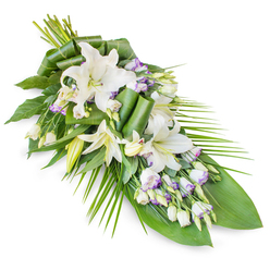 A refined sympathy spray in white and green is arranged on a stark white background, its gentle diagonal sweep echoing the quiet path of farewell. Large oriental lilies in pure, luminous white form the focal point, some blooms fully open and cupped like soft porcelain, others still sheathed in elegant buds that speak of unspoken memories and love that endures. Their petals appear almost satiny to the touch, while their subtle scent is imagined as clean and comforting rather than overpowering. Woven between the lilies, dainty white lisianthus (Eustoma) flowers cluster in small clouds, each delicate trumpet touched with a faint rim of lavender or pale purple, like the evening sky above Epping Forest just after sunset. Tightly furled buds dot the arrangement, adding rhythm and texture. The spray is crafted in a classic teardrop or sheaf style, broader and fuller at the top where stems and foliage meet, then gradually narrowing into a graceful point at the lower right, creating a sense of direction, as though the flowers are gently guiding a final journey. A foundation of rich green foliage grounds the tribute: broad, glossy leaves provide weight and calm, while long, spiky palm fronds arc outward to one side, adding movement and airiness. Some leaves are carefully rolled and looped, forming contemporary, almost architectural shapes that reveal an experienced florist's hand, the sort of thoughtful work families in Epping might choose for a crematorium or church service. The entire composition feels cool, peaceful, and dignified, suitable for expressing condolences or honouring a cherished life with a touch of understated elegance.