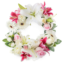 This open circular wreath, displayed against a bright white backdrop, feels like a soft spoken message of sympathy crafted by an experienced Epping florist. The ring is densely layered with white, pink, and deep magenta blooms, yet there is air and light between the petals, allowing each flower to be seen and appreciated. Majestic white lilies sit prominently around the circle, their velvety petals curling outward from green pistils dusted with golden pollen, suggesting purity and peaceful rest. Threaded among them are striking deep pink and fuchsia lilies, their vivid colour and speckled centres giving the wreath a subtle sense of movement and life. White gerbera daisies with dark, expressive centres are scattered throughout, their neat, radiating petals adding texture and a quiet optimism. Around them, soft pink roses, many in half-open bud, offer a blush of gentle colour, while creamy white roses in fuller bloom bring a traditional, dignified charm. Small white filler flowers, likely spray carnations or similar, are carefully placed to create a plush, unbroken circle without any harsh gaps. A base of glossy, layered greenery holds everything together, the leaves forming a natural frame that deepens the circular shape. The arrangement feels as if it could rest peacefully at a service in Epping town centre or accompany a family gathering near Stonards Hill, carrying with it a sense of tender remembrance, comfort, and enduring love.