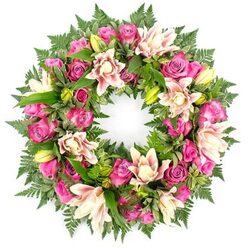 Placed against a clean white backdrop, this circular funeral wreath appears almost to float, its colours and textures forming a calm, unbroken ring of remembrance. At its core are clustered roses in vivid shades of fuchsia, magenta, and softer rose-pink, their petals layered like delicate fabric, some blossoms generous and open, others in tight buds that hint at stories still held close. Between these romantic blooms sit star-shaped double lilies in creamy white, blush pink, and pale peach, their petals thick and gently rippled, folding back to show softly dusted centres. A scattering of fresh, yellow-green lily buds punctuates the design, their smooth, tapered forms adding height and a note of quiet promise. The flowers rest on a bed of deep green foliage: fine, feathery fern fronds trace the outer circle, while polished leaves and touches of lighter, almost variegated greenery give the wreath depth and movement. The composition is balanced and symmetrical, as if lovingly arranged by an experienced local florist familiar with the quieter corners of Epping, from the leafy edges of Epping Forest to the streets near the station. Bright, even lighting brings out the contrast between the warm pink blooms and the cool green leaves, while the white background removes any distraction. The arrangement suggests tenderness and respect, making it a suitable choice for a funeral, wake, or celebration of life in Epping, where families seek a floral tribute that wraps their farewell in soft colour and lasting grace.