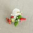 A finely detailed close-up of a single floral boutonniere resting on a softly textured, oatmeal-toned linen background, the sort of natural fabric you might see on a rustic table in an Epping High Street café. At the heart of the arrangement sits a pristine white Phalaenopsis orchid, its broad, velvety petals gently unfurling around a warm throat tinted with creamy yellow and a whisper of soft orange. The orchid's smooth surface catches the gentle, diffused light, giving the bloom a quiet glow as if it has just been prepared for a wedding at one of the local country venues on the edge of Epping Forest. Encircling this central flower are airy clouds of white baby's breath, each tiny floret adding a feathery, mist-like texture that softens the strong elegance of the orchid. Nestled close by, a glossy cluster of round red berries provides a vivid, cherry-like splash of festive colour, balanced by a few pale green buds that hint at new growth and freshness. Rich green leaves, some broad and pointed, others slender and more elongated, weave through the design, framing the central bloom and berries with a natural, garden-fresh feel. The stems are gathered neatly and wrapped in a smooth, vibrant red satin ribbon, tied in a small, careful knot with short trailing ends, making it ready to pin onto a lapel. The overall mood is one of refined celebration and thoughtful craftsmanship, perfectly suited to grooms, groomsmen, or prom guests seeking a sophisticated floral accent for special occasions in and around Epping.