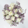 This image presents a graceful, circular bouquet photographed from directly above, its shape and colouring carefully designed to convey peace and remembrance for families in and around Epping. At the heart of the arrangement lie about a dozen beautifully formed white roses, their petals arranged in soothing spirals that move from firm, rounded buds to blossoms just beginning to open, and on to more mature flowers with exposed, layered centres. The colour is a calm, creamy white, deepening to a soft ivory and the slightest golden tint at the very core, like the pale glow of early morning light over Epping Forest. Surrounding and weaving through the roses are generous wisps of lavender-hued limonium, also called statice, its fine, clustered blooms creating a delicate, cloud-like frame. This gentle purple mist adds texture and visual depth, contrasting with the smooth velvet of the rose petals while never overpowering them. Small glimpses of green stems and minimal foliage lend a natural underpinning, keeping the palette refined and restrained. The flowers sit against a spotless white background, allowing the circular outline and subtle colour shifts to stand out clearly, as though the bouquet were floating. Crafted in the quiet, thoughtful style we often use at Flowers Epping for condolence and funeral pieces, this design feels intimate and sincere. It would be fitting for sympathy deliveries to homes, funeral directors, or chapels throughout Epping, offering a soft, reassuring presence and a dignified way to express support, remembrance, and unspoken care.