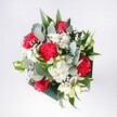 A hand-tied bouquet seen from above, overflowing with deep crimson roses and vivid pink-red carnations, their velvety petals spiralling open like small celebrations. Around them, white daisy-like chrysanthemums and clusters of tiny gypsophila form a soft, cloudlike halo, creating a bright contrast that feels as fresh as an early walk through Epping Forest after rain. Slender stems of eucalyptus weave through the arrangement, their silvery-green leaves adding a cool, contemporary twist against the richer tropical foliage. The greenery is layered and textural, with glossy dark leaves cradling the flowers and lighter, feathery fronds giving movement and lift, so the bouquet feels full but never heavy. Light catches on each petal edge, revealing variations of scarlet, cherry, and soft blush within the reds, while the whites stay crisp and clean, like new linen. You can almost sense the gentle, mixed fragrance: the classic sweetness of roses, the spicy hint of carnations, and the faint herbal note of eucalyptus. The bouquet suggests joy and affection without formality, perfect for birthdays, promotions, or welcoming someone home along High Street or Station Road in Epping. Crafted with the practiced hands of a local florist, the flowers are gathered in a neat, round shape that sits comfortably in the palms, ready to be placed in a favourite vase on a kitchen table, windowsill, or office desk, where their colour and energy can brighten daily life and quietly mark a meaningful moment.
