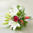 Displayed at a soft diagonal on a pale, woven fabric backdrop, this bouquet feels like it has just been set down on a table overlooking Epping Forest after a ceremony. Full-bloomed white oriental lilies dominate the arrangement, their open trumpets revealing creamy petals edged with a subtle ruffle and sprinkled with faint reddish freckles that lead the eye toward the centre. Alongside them, slender green buds stand upright, still tightly closed, suggesting the bouquet will continue to change and unfold over several days. Cradled in the midst of this white elegance is a single, luxurious red rose, its deep crimson petals packed closely in a flawless spiral, adding intensity and a strong romantic focal point. Around it, two soft, tufted globes of 'Green Trick' dianthus glow in fresh, mossy green, offering a tactile contrast to the smooth, satin texture of the lilies and rose. Delicate sprigs of baby's breath weave between the larger blooms like tiny white stars, while shiny red hypericum berries cluster at intervals, their round shapes and rich colour hinting at winter celebrations or chic barn weddings near Epping and Theydon Bois. The entire composition is supported by abundant foliage: broad, polished leaves provide depth, while fine, grass-like strands extend outward, giving the bouquet a sense of movement and airy lightness. The stems are gathered together in a precise bundle and wrapped in a lustrous red satin ribbon that catches the light, the tied end positioned neatly towards the lower right. Soft, natural illumination and gentle shadowing reveal every curve and texture, capturing a design ideal for bridal parties, anniversary deliveries, or romantic surprises across the Epping area.