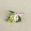 A delicately handcrafted boutonniere rests on a softly textured, light beige fabric that resembles natural linen, the neutral background allowing every petal and ribbon to stand out with clarity. At the heart of the design sits a single white alstroemeria bloom, its broad petals gently flaring open to reveal fine reddish-brown speckles that gather near the throat of the flower, like careful brushstrokes on porcelain. Just beside it, a compact, lime-green cone of tightly packed buds introduces a striking, sculptural form, its surface almost scale-like and glistening with freshness. Wisps of white baby's breath float through the composition, their tiny clustered blossoms creating a cloud-like halo that softens the stronger lines of foliage. Dark green, lance-shaped leaves cradle the flowers, while slender blades of grass-like greenery weave and curl, adding movement and a sense of natural ease. The stems are gathered neatly and finished with a pastel pink satin ribbon, tied into a precise little bow that glows softly against the beige backdrop, adding a romantic, celebratory touch. The lighting is even and gentle, as if filtered through an overcast Epping morning, revealing the subtle textures of the petals and fabric without any harsh glare. This small floral piece, perfect for a lapel at a wedding in Epping or a prom near the High Street, conveys quiet elegance, freshness, and care, embodying the kind of intimate detailing local florists bring to special days.
