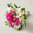 Resting on a pale beige, gently textured linen surface, this hand-tied bouquet feels like a snapshot of a perfect spring morning in Epping. At the centre, large hot pink peonies are open to their fullest, each bloom a mass of soft, layered petals that create a velvety, almost cushion-like focal point. Nestled among them, white alstroemeria blossoms stretch out on slender stems, their narrow petals brushed with faint pink and maroon streaks that lend a painterly delicacy to the arrangement. Here and there, slim green buds and upright filler flowers break through the peonies and lilies, adding spikes of fresh texture and the sense that more blossoms are just about to unfurl. Deep green foliage curves around the blooms, grounding the bright colours and giving the bouquet an organic flow, as though it could have been gathered after an early walk near Epping Forest or along Bell Common. All the stems are pulled tightly together into a smooth, tapered handle, then wrapped in a blush-pink ribbon that circles them with a soft, satin sheen, ready to be cradled by a bride, bridesmaid, or someone marking a special anniversary. The light, neutral background lets the magenta and white tones glow without distraction, highlighting every ruffle and speckle. The bouquet feels airy yet abundant, radiating romance, happiness, and new beginnings, like flowers chosen for a wedding at a local Epping venue or for same-day delivery to surprise someone at home. It captures that blend of elegance and natural charm local florists create so often for celebrations across the town.