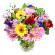 The photograph presents a flourishing mixed bouquet arranged in a classic clear glass vase, set against a bright white background that highlights every colour and curve. Dominating the centre are opulent deep red roses, their petals velvety and layered, giving the arrangement a core of rich, romantic intensity. Just beside them, two radiant yellow gerbera daisies with dark brown-orange centres stretch out their wide, daisy-like petals, adding a joyful, sunlit quality that recalls a bright afternoon wandering through Epping's market and nearby streets. Around these standout blooms, a soft ring of pink and lavender daisies or chrysanthemums spreads outward, their many slim petals and neat yellow centres lending volume and a cushiony softness, as if the bouquet were wrapped in a pastel cloud. Threaded between them, elegant purple and lilac lisianthus blooms arch gracefully on slender stems, their bell-shaped flowers and gently ruffled edges bringing cool, refined contrast. Nestled here and there are glossy red hypericum berries, small and round like tiny ornaments, which introduce an appealing textural surprise. A tapestry of foliage in assorted greens fills in the spaces, from deep, shiny leaves to lighter, more delicate sprigs that create subtle height and rhythm, evoking a freshly gathered feel from gardens around Epping and the leafy paths towards the forest. The clear glass vase reveals the straight, carefully cut stems and clear water, underscoring the freshness and artistry of the design. Overall, the bouquet radiates happiness and thoughtful care, ideal for delivering birthday wishes, congratulations, or simple everyday cheer to homes and offices across Epping.