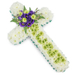 A dignified funeral cross arrangement fills the frame, its symmetrical shape clearly defined against a smooth white background. Every part of the cross, from the gently flared horizontal arms to the long vertical stem, is covered with a dense layer of snowy white chrysanthemums, their small petals forming a gently textured surface that feels calm and embracing. A crisp border of vivid, leaf-green ribbon or closely packed greenery runs neatly around the outside, outlining the Christian symbol with clarity and giving the tribute a fresh, contemporary finish. At the very centre of the cross, where the arms meet, a striking cluster of flowers creates a focal point. Deep purple lisianthus blossoms open in soft, velvety layers, paired with bright lime green button chrysanthemums whose rounded forms and zesty colour lift the design. Fine, dark green fern fronds fan out behind this cluster, introducing a hint of wild, woodland character, like the greenery found along the paths leading towards Epping Forest. Down the length of the vertical arm, a strip of lime green flowers is carefully stitched into the white base, forming an elegant central panel. Over this, slim, pale wires are gently laid in a loose lattice, adding subtle texture and crafted detail. The overall impression is one of quiet reverence and comfort, ideal as a memorial cross or graveside tribute for services in Epping churches or local cemeteries, expressing faith, remembrance, and gentle support for the bereaved through its soothing palette of white, green, and purple.
